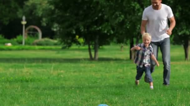 Отец и сын играют в мяч в парке — стоковое видео