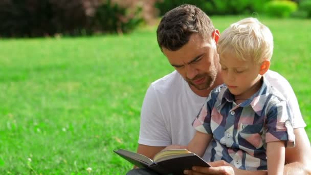 Otec a syn čtení knihy v parku — Stock video