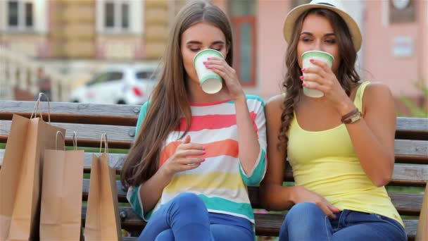 Twee meisjes op een bankje drinken koffie — Stockvideo