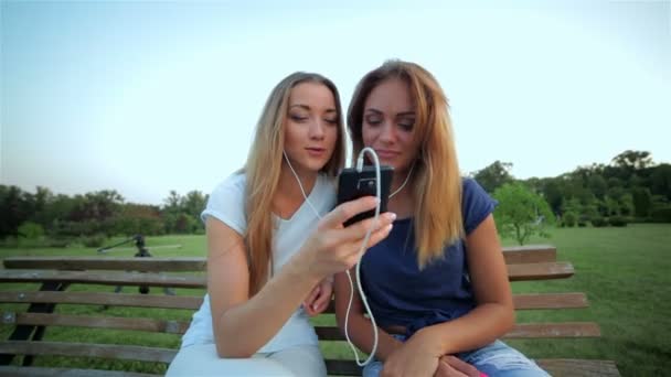 Девушки слушают музыку вместе на плеере — стоковое видео