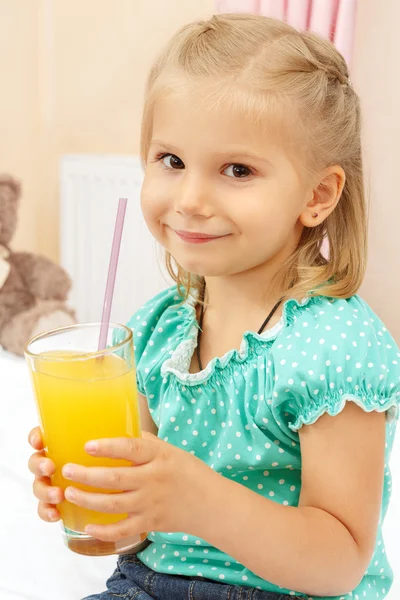Happy little girl with glass of orange juice Royalty Free Stock Photos