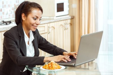 İş kadını mutfakta dizüstü bilgisayar kullanarak