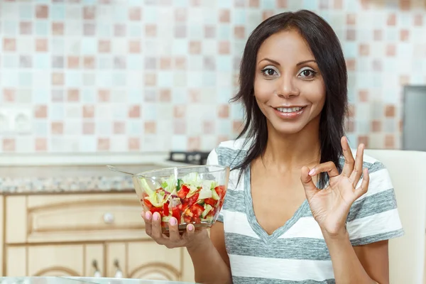 O femeie frumoasă care mănâncă salată proaspătă în bucătăria modernă — Fotografie, imagine de stoc