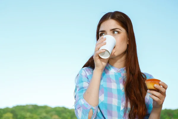 Ganska ung kvinna dricker kaffe på park — Stockfoto