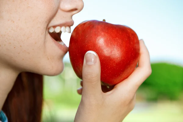 Vacker flicka äta äpple i parken — Stockfoto