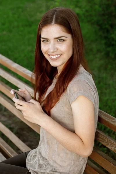 Retrato de una joven en el parque de mensajes de texto por teléfono — Foto de Stock