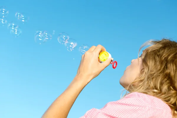 Vacker ung blond flicka blåser såpbubblor i himlen. — Stockfoto