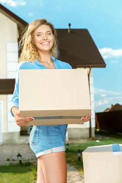 Mujer joven llevando cajas a casa nueva —  Fotos de Stock