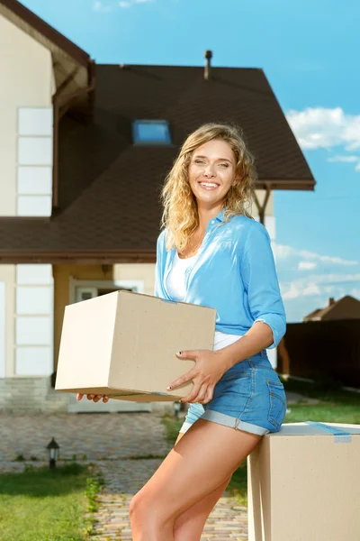 Mujer joven llevando cajas a casa nueva —  Fotos de Stock