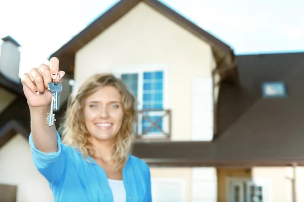 Chica feliz con llaves al lado de su nueva casa —  Fotos de Stock