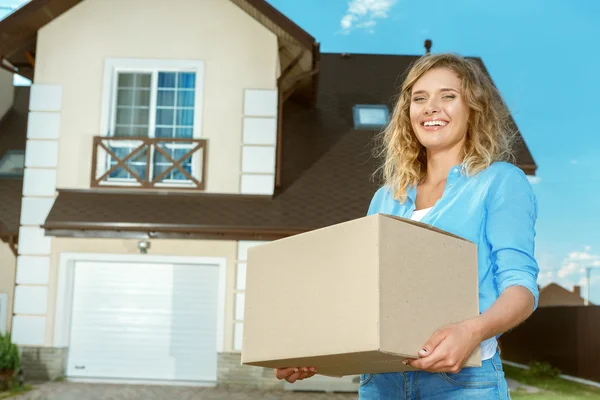 Mujer joven llevando cajas a casa nueva —  Fotos de Stock