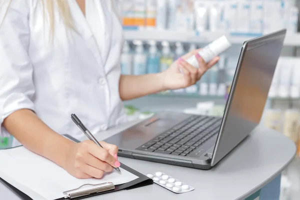 Närbild på en apotekare att göra anteckningar från den bärbara datorn — Stockfoto