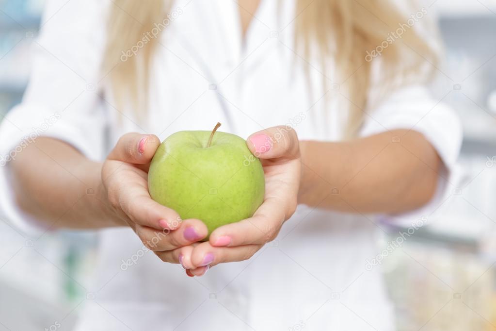 Close up of a pharmacist holding an apple