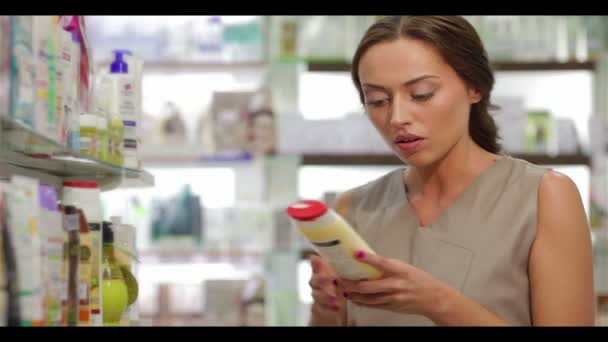 Mooie jonge vrouw op zoek naar goede shampoo — Stockvideo