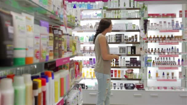 Mooie jonge vrouw op zoek naar goede shampoo — Stockvideo