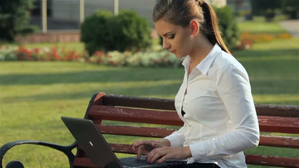 Fille travaillant sur ordinateur portable sur le banc — Video