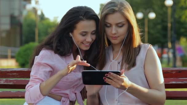 Две девушки слушают музыку на планшете — стоковое видео