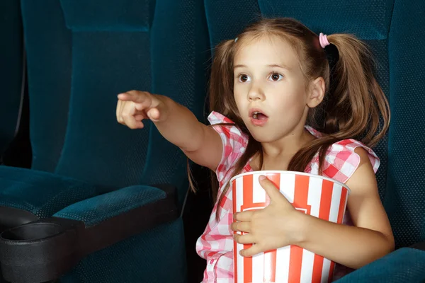 Маленькая девочка, указывающая на экран во время фильма — стоковое фото