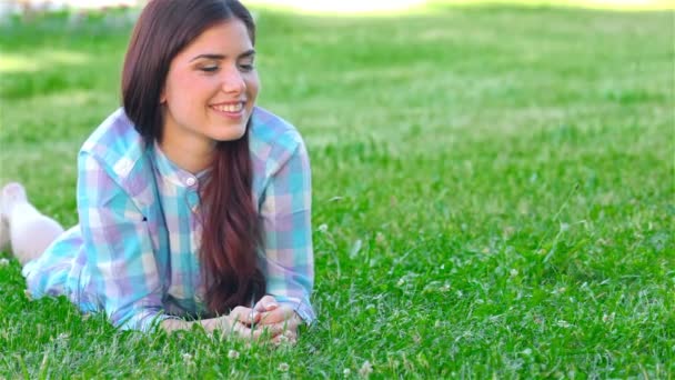 Mädchen entspannt sich im Freien und sieht glücklich und lächelnd aus — Stockvideo