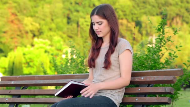 Attractive girl with a diary sitting on the bench — Stock Video