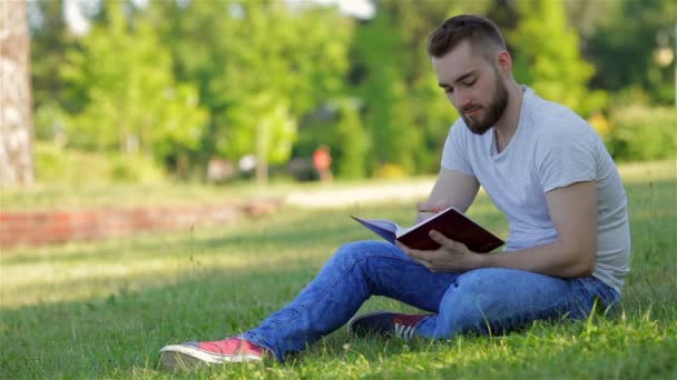 Young man sitting in the park with his diary — Stock Video