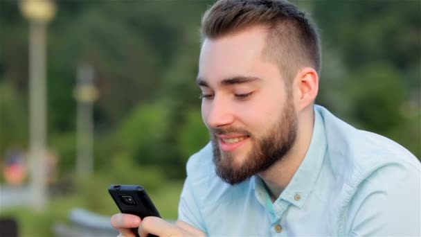 Young man with mobile phone in park — Stock Video