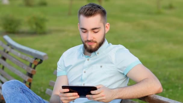 Junge sitzt mit Tablet auf Bank — Stockvideo