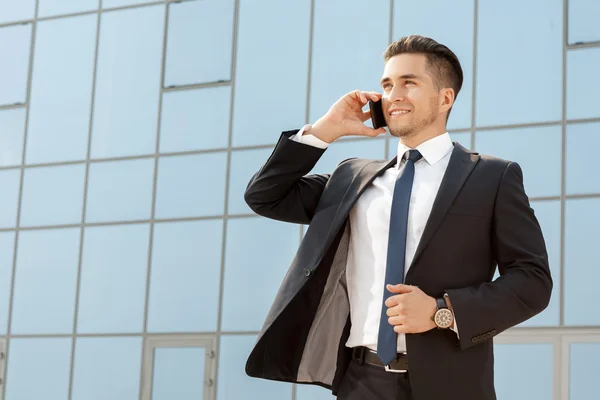 Handsome businessman talking on his phone outdoors — Stock Photo, Image