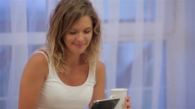 Güzel kız yatakta kahve içme tablet kullanma