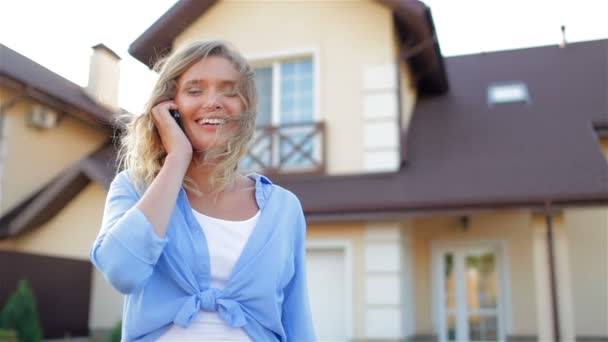 Bella ragazza che parla al telefono accanto alla nuova casa — Video Stock