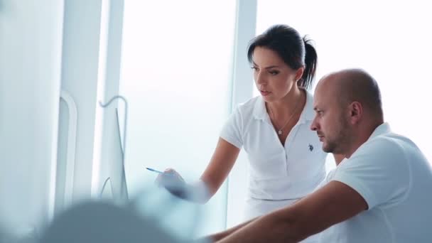 Twee tandartsen bespreken een patiënt op computer — Stockvideo