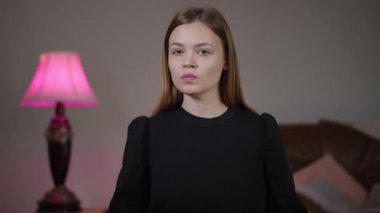 Beyaz kadın yeterince sarıldı, kararlı bakışlar kağıt üzerinde kanlı el izleri, pembe lamba ve yatak odası arka planı, meydan okumanın ve güçlendirmenin yakın portresi,