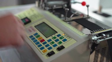 Kapalı etiket yazıcı kontrol paneli renkli tuş takımı ve parmak basma düğmelerini gösteriyor. Küçük LCD ekran, kağıt besleme silindiri, metal klemp, teknisyen