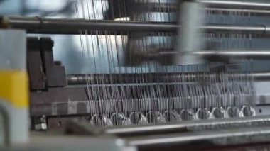 Yakın plan endüstriyel dokuma tezgahı makinesi yüksek hızlı iğneler ve iplikler gösteriyor desenli kumaş, metalik rehberli ve sensörlü ritmik hareket, serin