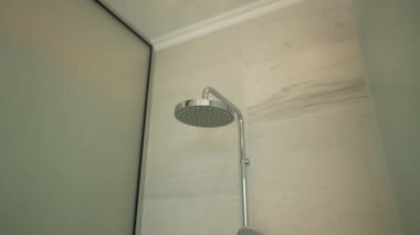 Bardakta sağanak yağmur başlığı, desenli fayans duvarda krom fikstür, buzlu cam kapı, yumuşak sıcak aydınlatma, kaplıca atmosferi, hafif sprey hazır.