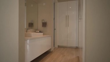 Modern banyo kibri tarafsız paleti batırır yumuşak ışıklandırma sıcak hava yaratır, iç mimar düzeni denetler, ev sahibi sabah rutinini hazırlar,