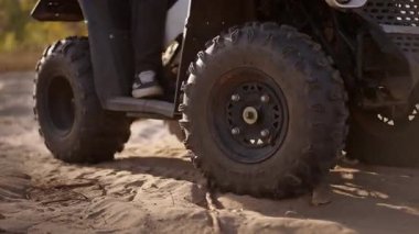 Yakın çekim lastiği tozlu kum yüzeyini tekmeliyor, zemini ısırıyor, güneş ışığında dönen tanecikler süspansiyon yanıt verirken, teknik olarak