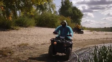 AVT 'lerin yarış kıyı şeridindeki sürücüler, kumlu nehir kenarındaki tozları tekmelerken mavi ceketli liderleri sıkı virajlar alırken sarı ceketli takipçiler