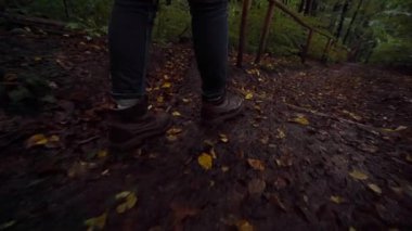 Çamurlu orman yolunda yürüyen botlar, bulutlu sonbahar yürüyüşü sırasında ayak altında çatırdayan ıslak yapraklar alçak açılı kamera ayak seslerini, nemli toprak dokularını, dağınık ayak seslerini kaydediyor.