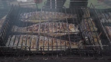 Metal rafta bütün balıkların cızırdadığı dumanlı kömür ızgarası. Elleri altın sarısı sardalyaları parlayan kömürlerin üzerinde döndürüyor. Yoğun duman sürükleniyor.