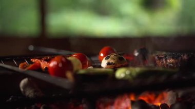 Sebzeli ve közlü ızgara, kiraz domatesleri, kabak dilimleri, şişler ve kömürleşmiş işaretler, yükselen dumanlar, meyveleri ayarlayan maşalar, ılık maşalar.