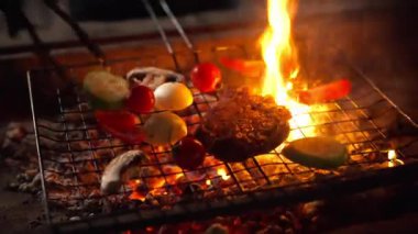 Canlı sebzeli cızırtılı biftek kömürün üstünde kavruluyor, şef maşaları eti çeviriyor, ot jöleli karamelize ediyor, sulu dokular ve baharatlı aroma, arka bahçede akşam yemeği.