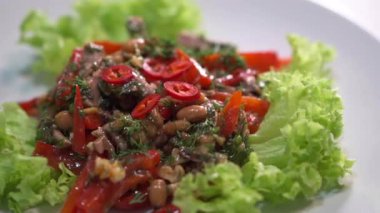 Etli, kırmızı fasulyeli, dolma biberli, cevizli ve kırmızı biberli iştah açıcı salata. Kıtır marul yapraklarından oluşan bir yatakta servis ediliyor.