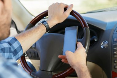 Arabada otururken telefon kullanan genç adam