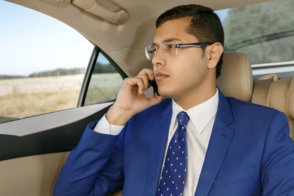 Arabanın arka koltukta telefonda konuşan işadamı