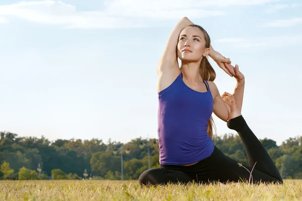 Attractive young woman stretching in the park — Stock Photo, Image
