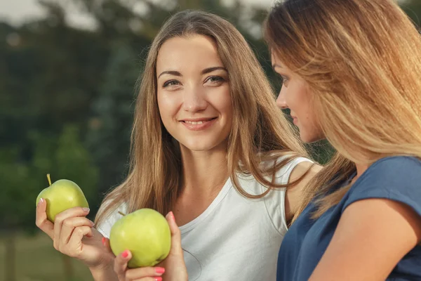 Två unga flickor med äpplen i parken — Stockfoto