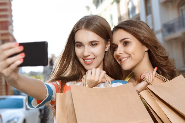 Kaksi ystävää tekee selfie kanssa ostoskassit kuvapankkikuva
