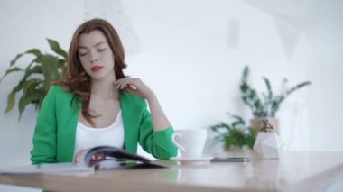 Genç kız kahve molası sırasında dergi okuma