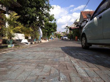 Asfaltlı yolları ve açık mavi arabaları olan bir ev. Sabahleyin görüldü